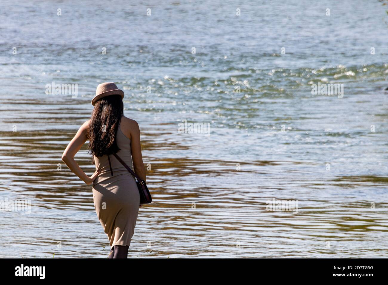 Jeune femme en robe, avec une hutte sur sa tête en regardant à l'eau Banque D'Images