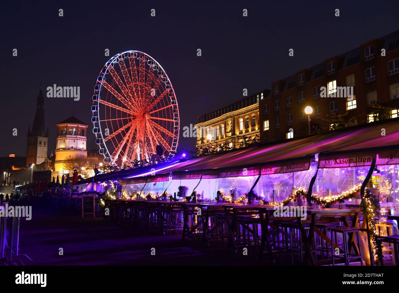 Promenade du Rhin avec restaurant extérieur éclairé « Kasematten » pendant les fêtes. Grande roue et tour du château en arrière-plan. Banque D'Images