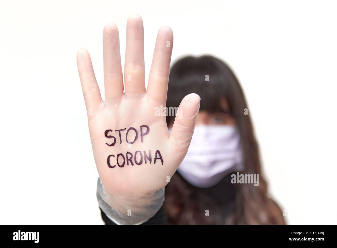 Femme portant un masque facial et des gants montrant sa paume Avec l'écriture de 'Stop Corona' Banque D'Images