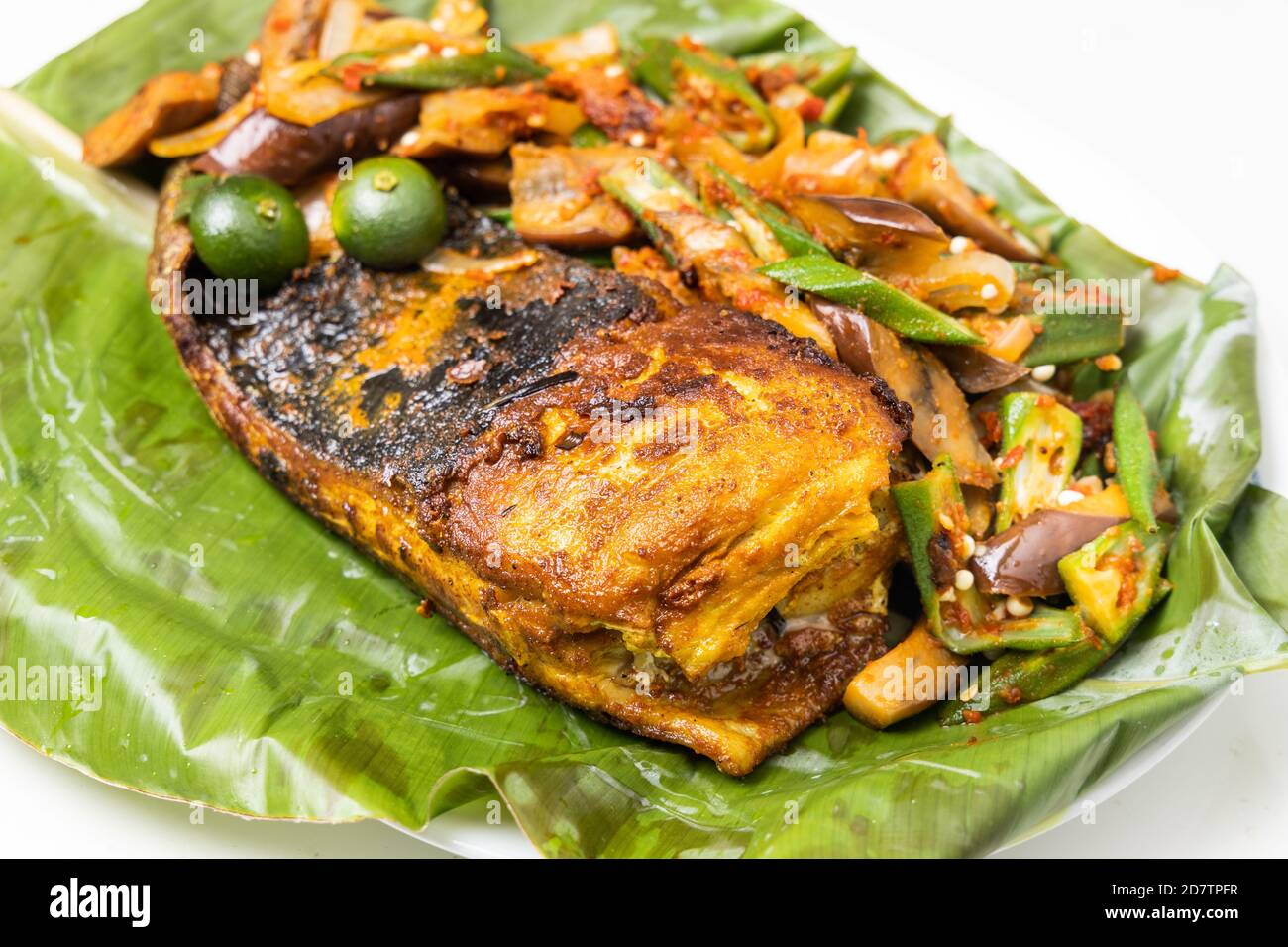 Gros plan de poissons grillés populaires aux épices et aux légumes servi sur une feuille de banane Banque D'Images