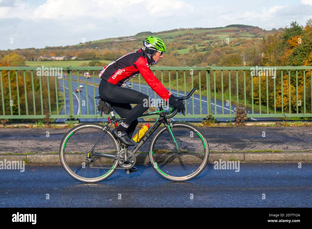 Chorley CC cycliste mâle équitation Cube atteindre sport route vélo sur la route de campagne traversant le pont d'autoroute dans la campagne Lancashire, Royaume-Uni Banque D'Images