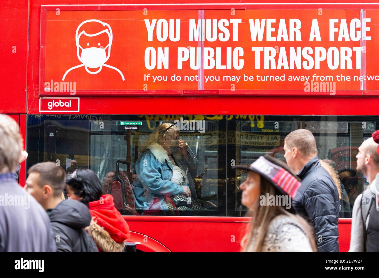 Les manifestants défilent devant une femme portant un masque sur un bus portant une signalisation COVID-19 lors d'un rassemblement anti-verrouillage à Londres, le 24 octobre 2020 Banque D'Images