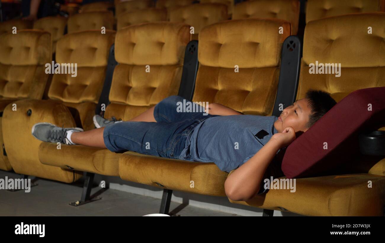 Un garçon posé sur le fauteuil et regarder un film au cinéma. Banque D'Images