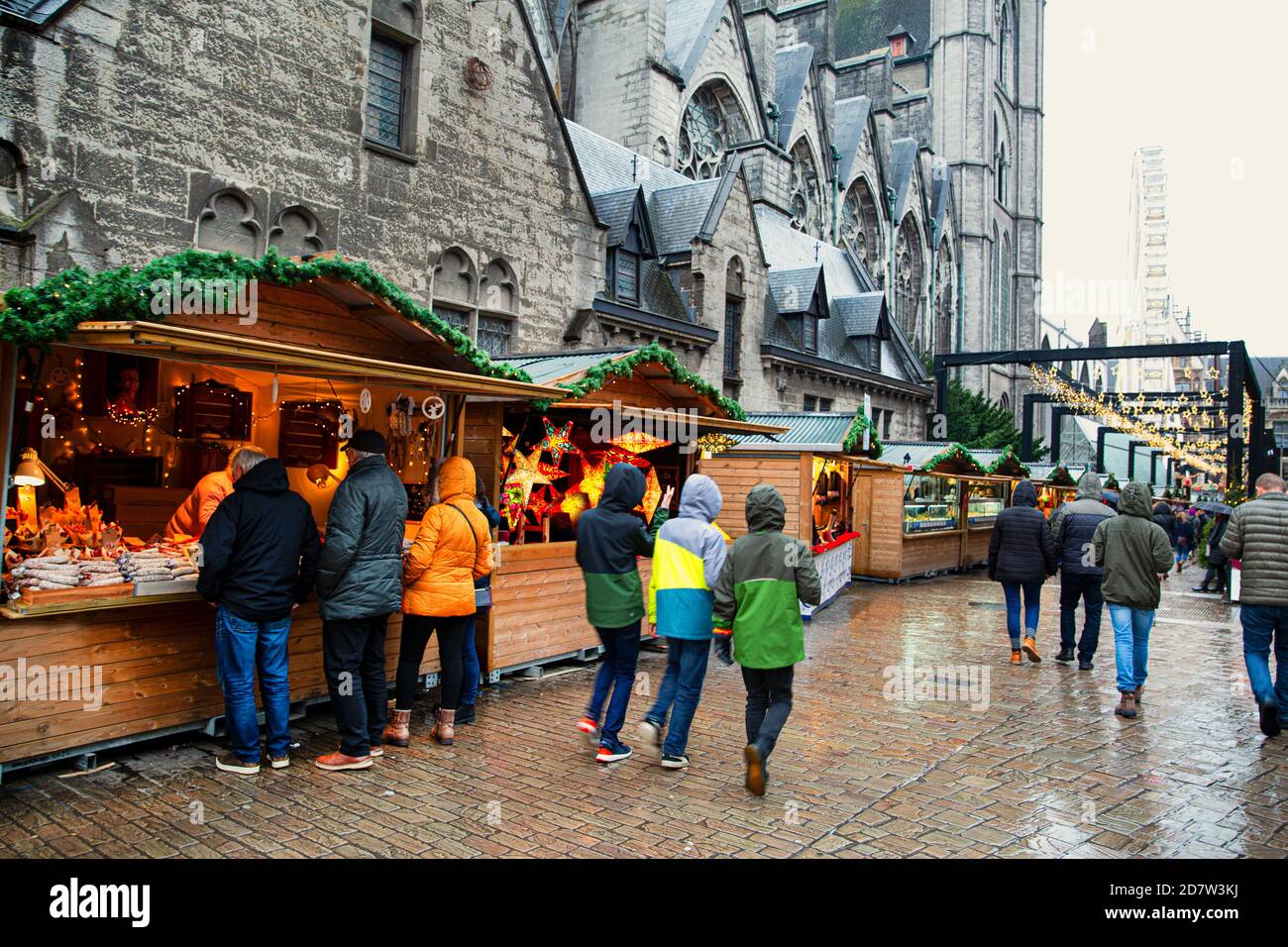 Marché de Noël à Gand, Belgique. Les gens qui marchent, les kiosques de noël, les pavillons et l'église en arrière-plan. Banque D'Images