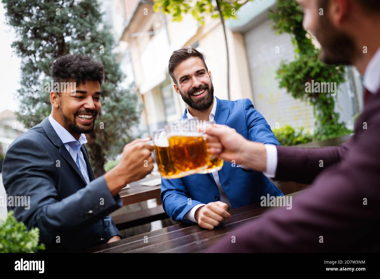 Les hommes d'affaires sont en train de boire de la bière, de parler et de sourire tout en se reposant au pub Banque D'Images