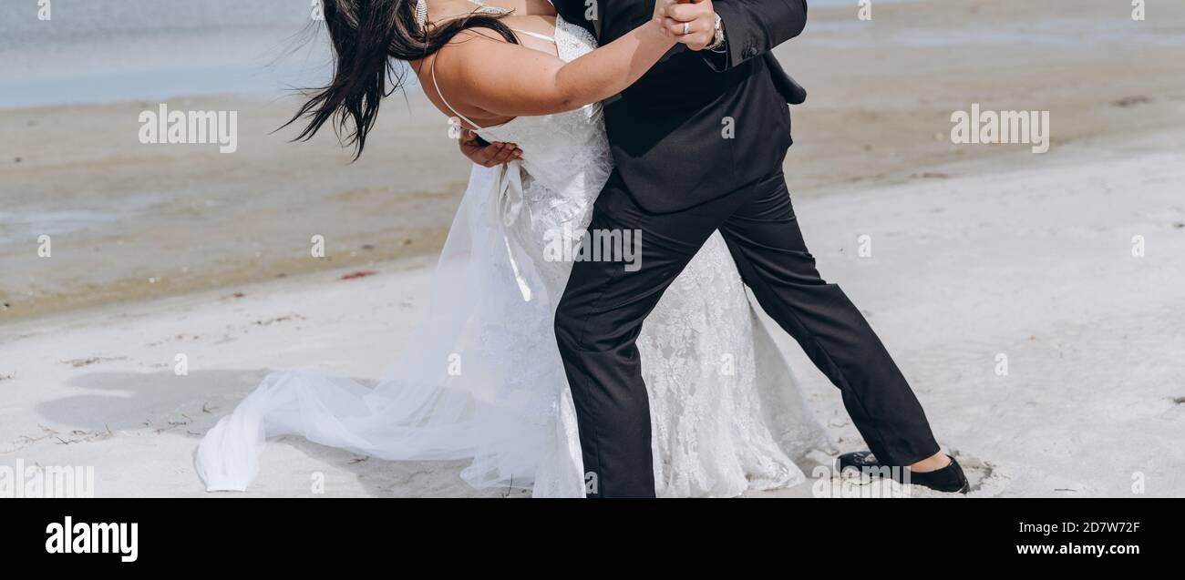 Couple de mariage dansant chaud à la plage, jeune mariée porte la robe blanche. Concept de photographie. Banque D'Images