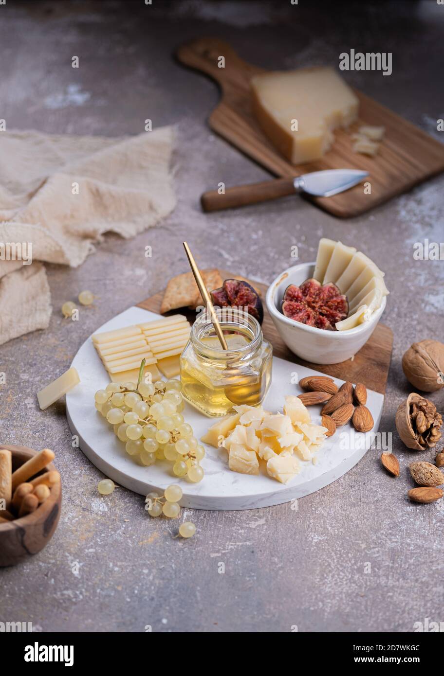 Assortiment de fromages sur plateau de marbre avec figues, noix, raisins et miel Banque D'Images