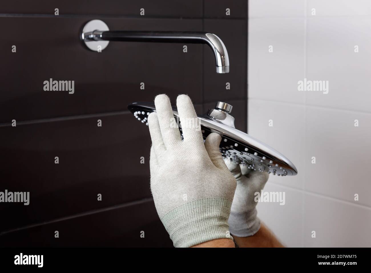 Les mains du travailleur installent la tête du robinet de douche intégré. Banque D'Images