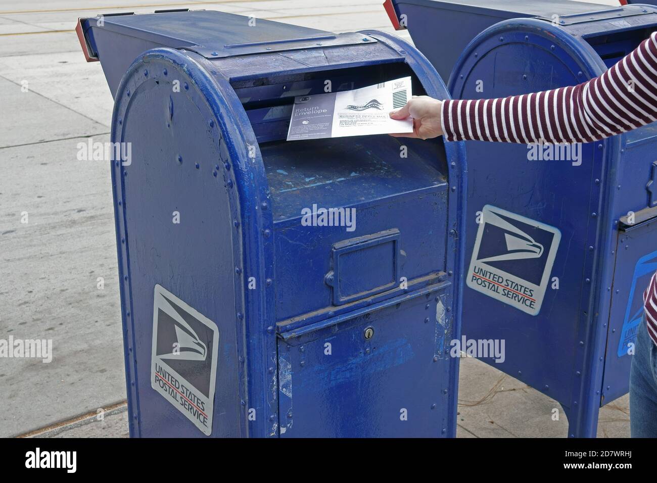 Los Angeles, CA / USA - 25 octobre 2020: Une femme met un bulletin de vote pour l'élection présidentielle de 2020 dans une boîte de scrutin officielle dans L.A. Banque D'Images