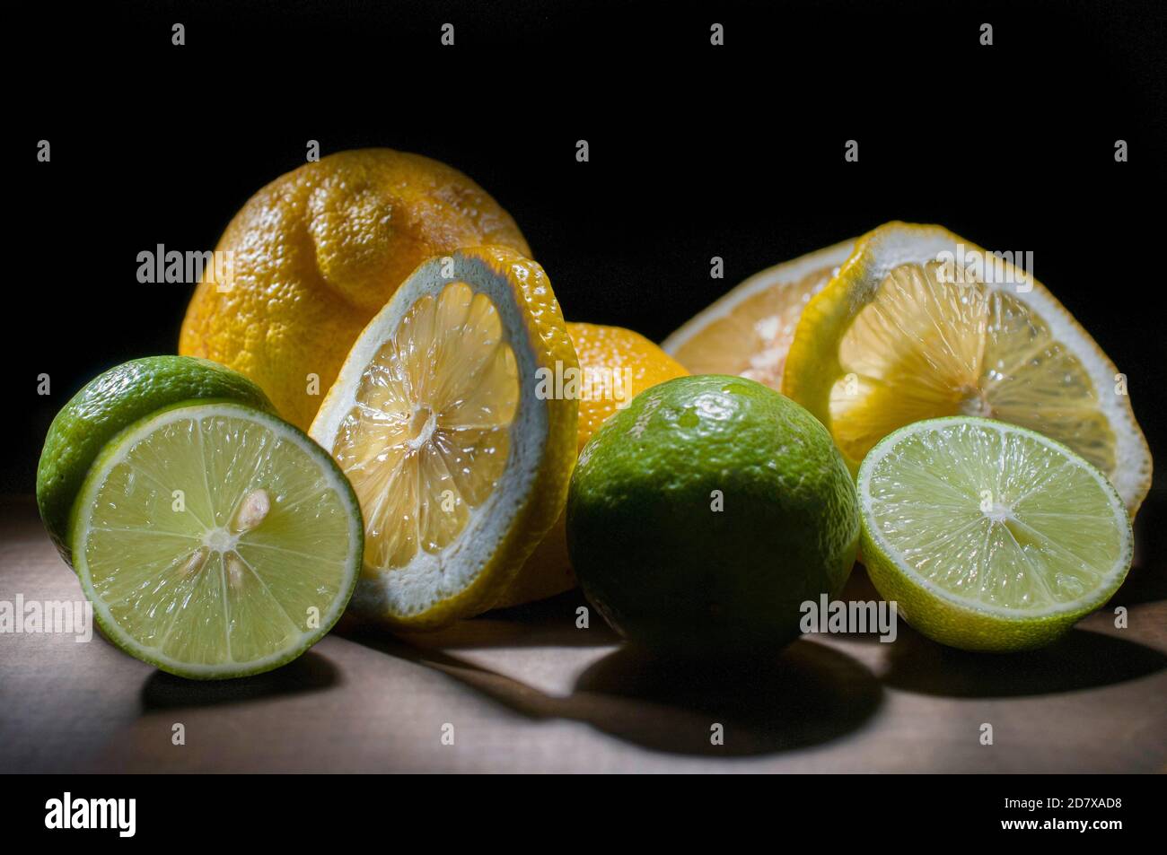 Encore la vie, les citrons verts et jaunes sur une table rustique en bois, les tranches et les citrons entiers dans a b manque de fond concepts de fruits citriques Banque D'Images