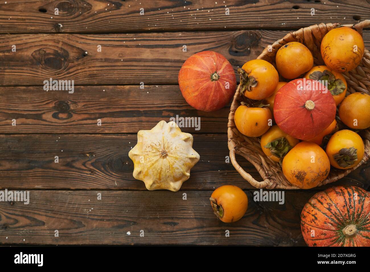panier avec une récolte de persimmons et de citrouilles sur une table en bois. Style campagnard Banque D'Images