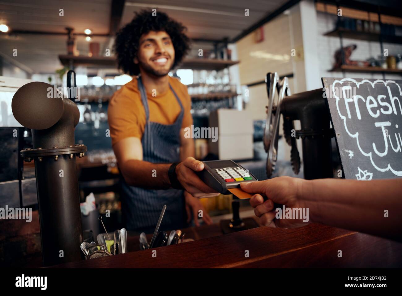 Serveur tenant la machine à glisser la carte de crédit pendant que le client tape le code dans un café moderne Banque D'Images