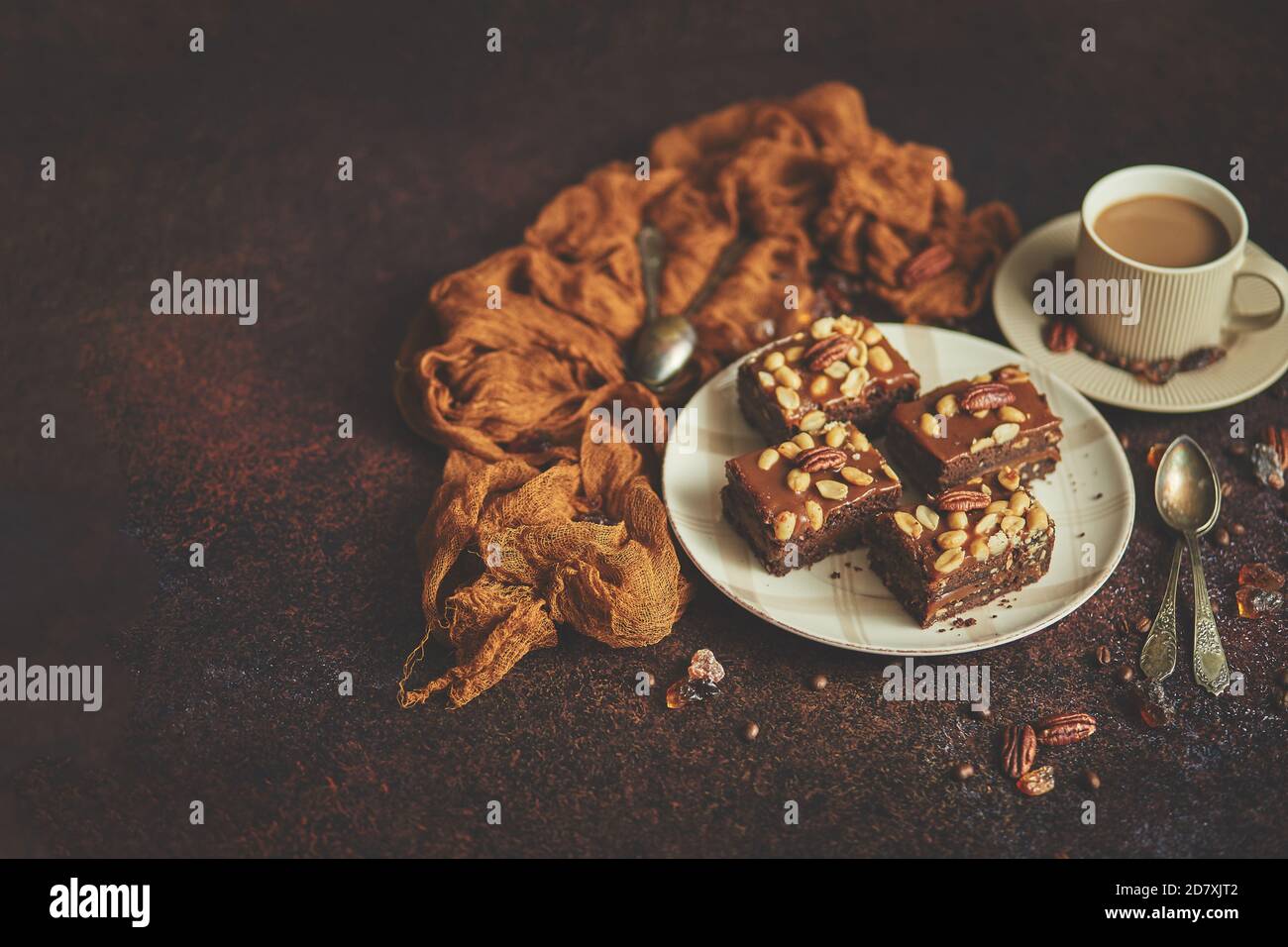 Les morceaux carrés de délicieux gâteau au caramel avec des arachides et noix du brésil servies avec du café au lait Banque D'Images