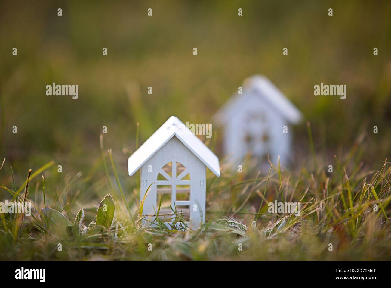 Chiffres de petites maisons en bois blanc sur l'herbe en gros plan. Le chalet est dans un endroit rural et village, bâtiment, projet, déménagement, hypothèque, loyer Banque D'Images