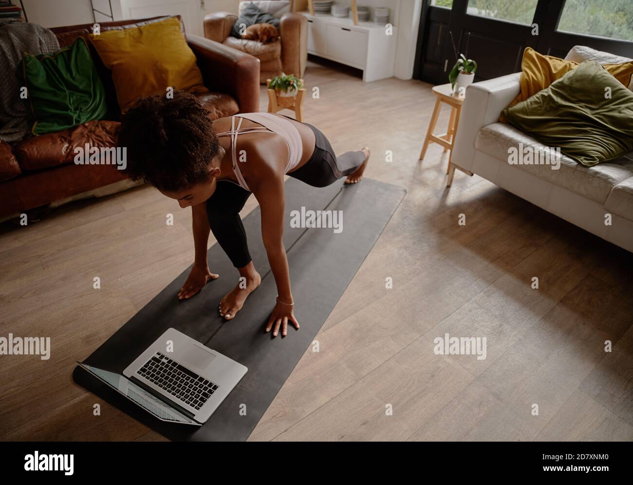Vue en grand angle d'une femme regardant une vidéo sur un ordinateur portable faites de l'exercice sur un tapis de yoga à la maison Banque D'Images