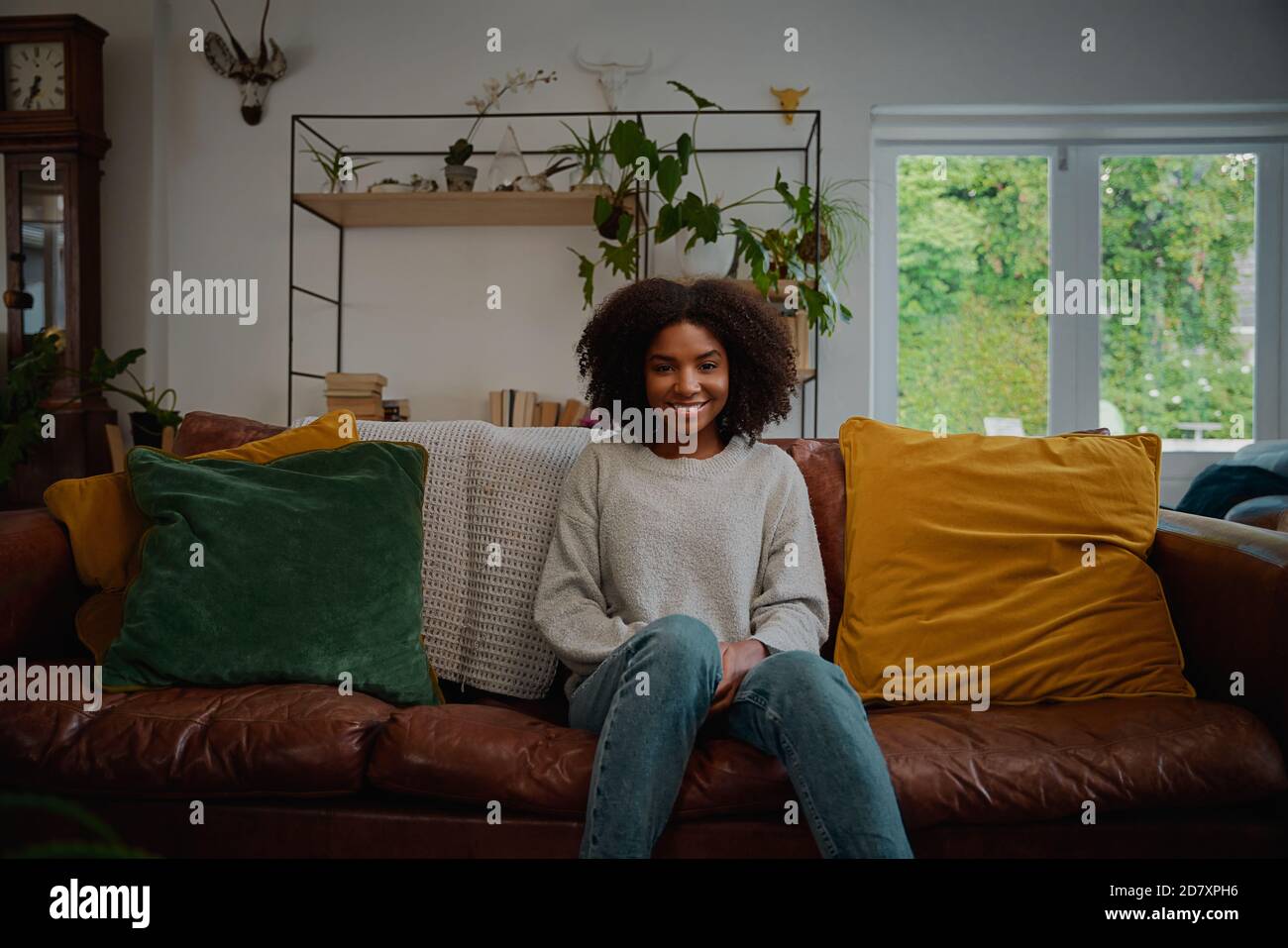 Portrait d'une belle femme aux cheveux bouclés assis sur un canapé avec coussin Banque D'Images