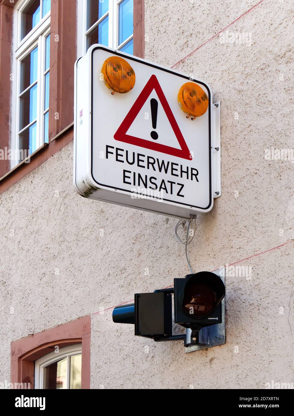 Panneau sur une façade indiquant que les voyants d'alerte jaunes clignotent lorsque les pompiers sont en action. Mit Warnleuchten für Feuerwehr Banque D'Images