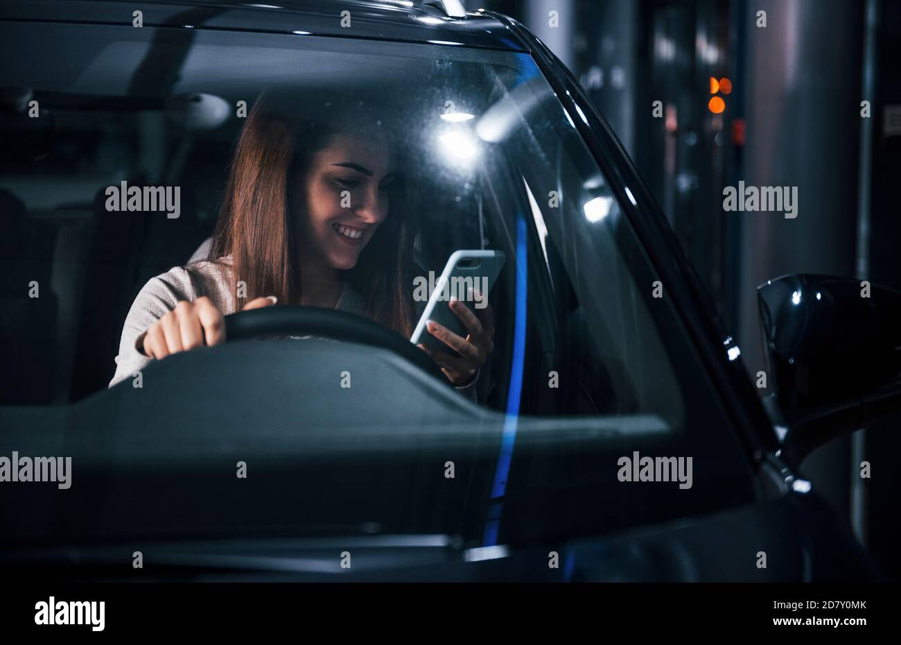 Jeune femme est à l'intérieur de toute nouvelle automobile moderne avec téléphone Banque D'Images