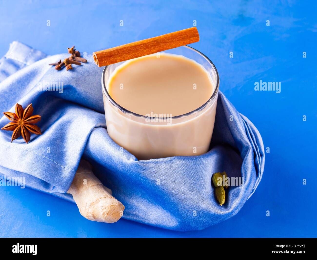 Thé Chai de masala. Boisson traditionnelle indienne - thé masala avec diverses épices. Verre de thé masala sur fond bleu Banque D'Images