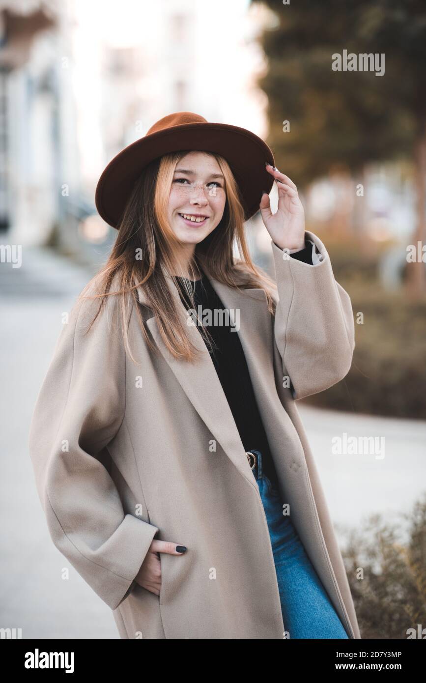 Une adolescente souriante de 14-15 ans portant un chapeau et un manteau  d'hiver marchant dans la rue de la ville à l'extérieur de près. Regarder  l'appareil photo. Teenagerhood Photo Stock - Alamy
