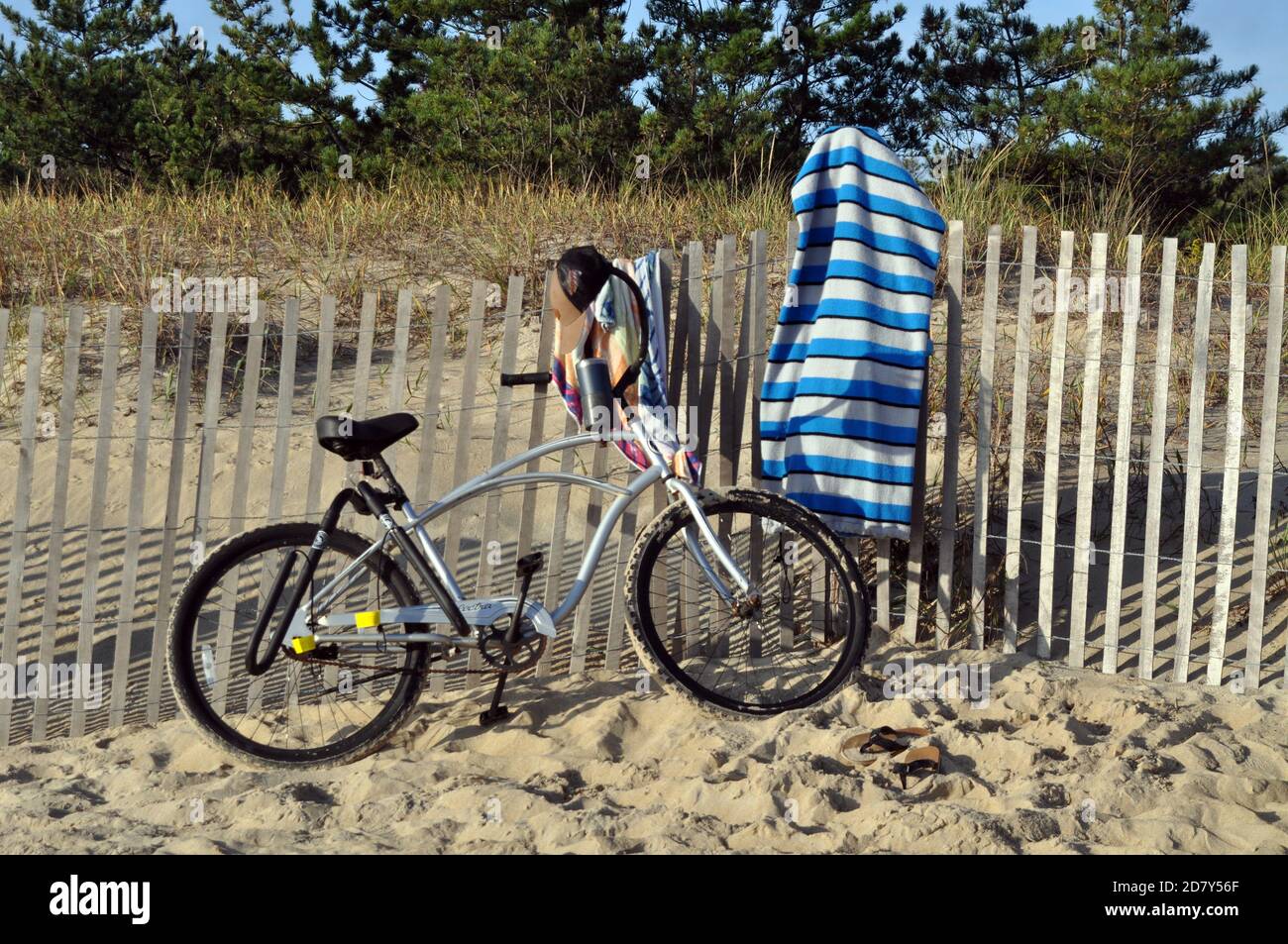 Une bicyclette à côté d'une clôture de plage avec une serviette accrochée à la clôture Banque D'Images