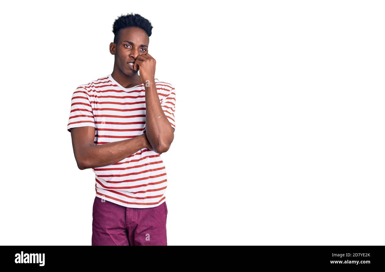 Jeune afro-américain portant des vêtements décontractés, avec des mains sur la bouche qui mordant les ongles. Problème d'anxiété. Banque D'Images