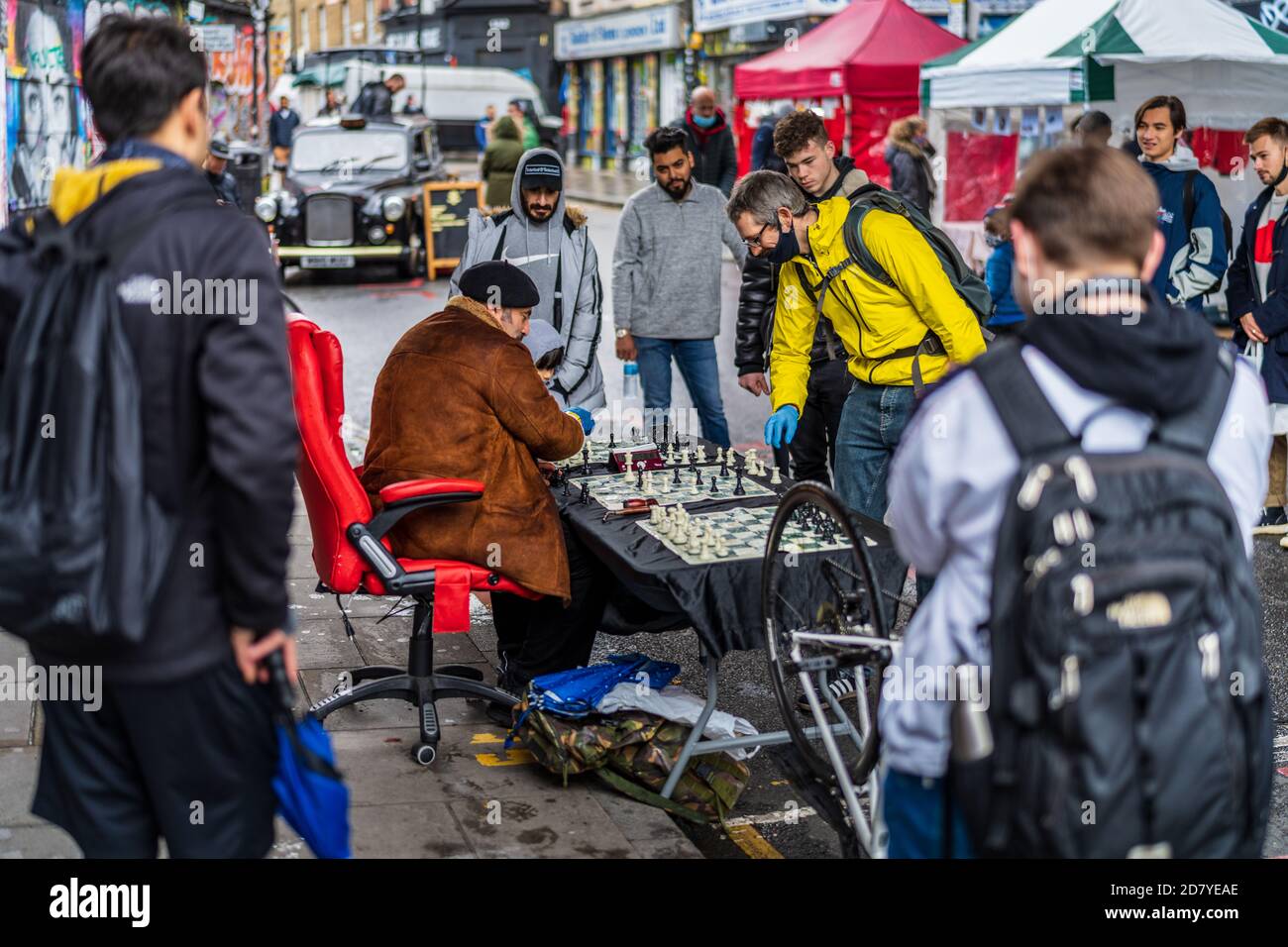 Street Chess Brick Lane Londres - un joueur d'échecs joue Matchs d'échecs rapides avec les touristes et les passants dans le populaire Londres Marché du dimanche de Brick Lane Banque D'Images