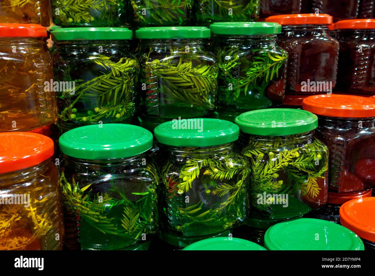 Pots en verre avec différents types de miel avec des feuilles de sapin et de tilleul sur le marché. Banque D'Images