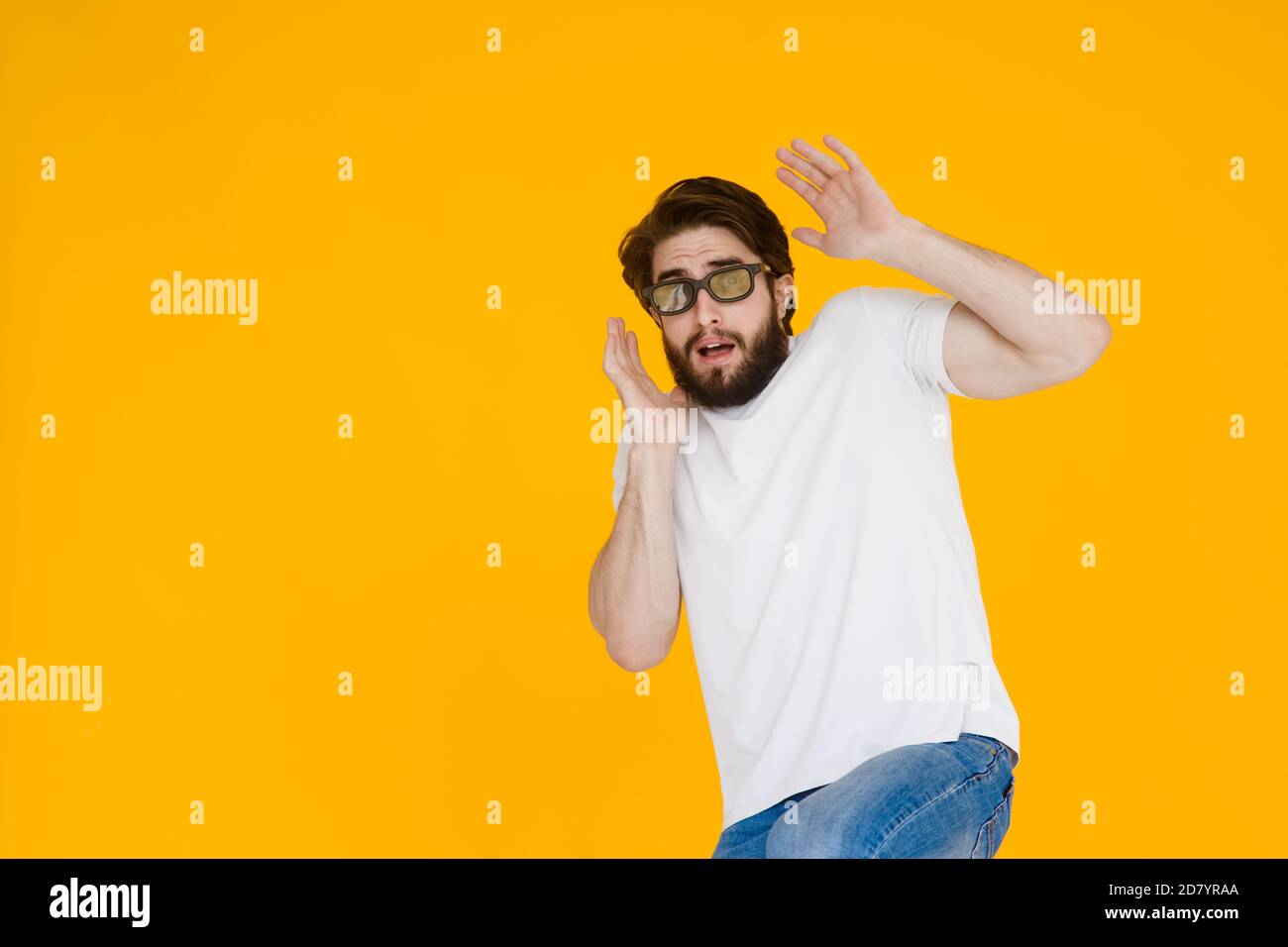 Portrait d'un homme barbu et effrayé en lunettes 3D à la bouche ouverte et aux yeux grands, sur fond jaune. Banque D'Images