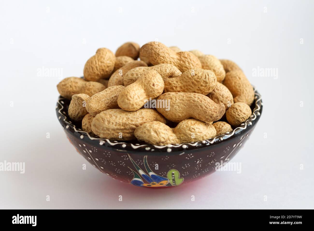 arachides crues dans la coquille sur la coupe d'argile sur fond blanc Banque D'Images