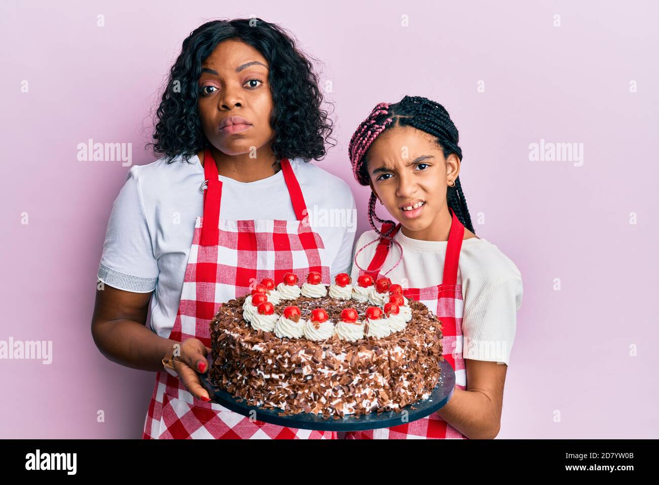 Belle Mere Et Fille Afro Americaine Portant Un Tablier Boulanger Tenant Un Gateau Maison D Expression Sans Cluess Et Confuse Doute Concept Photo Stock Alamy