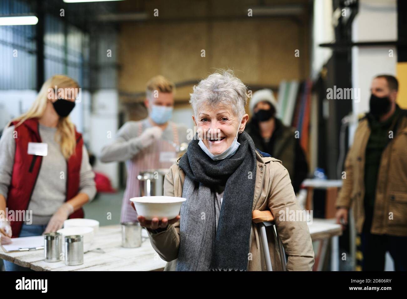 Bénévoles servant de la soupe chaude pour les sans-abri dans un centre de dons de charité communautaire, concept de coronavirus. Banque D'Images