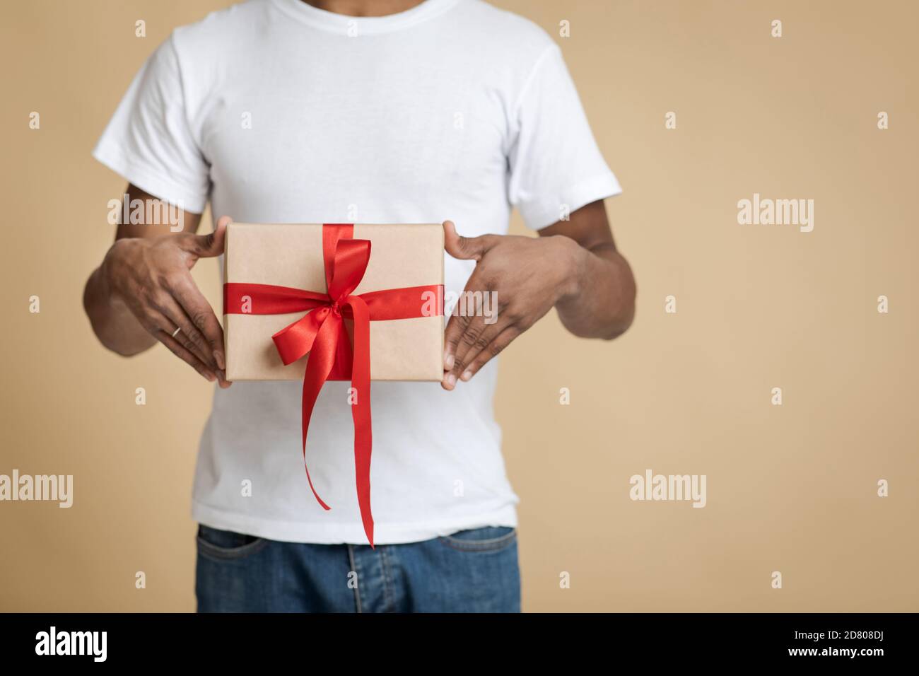 Surprise pour Noël et fête de famille. Homme afro-américain en t-shirt blanc avec cadeau Banque D'Images