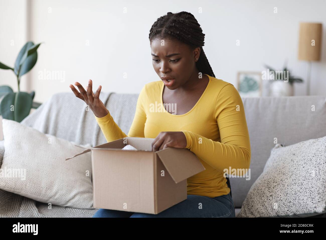 Colis incorrect. Une femme noire frustrée a été choquée lors du déballage de la boîte, souffrant d'une erreur d'expédition Banque D'Images