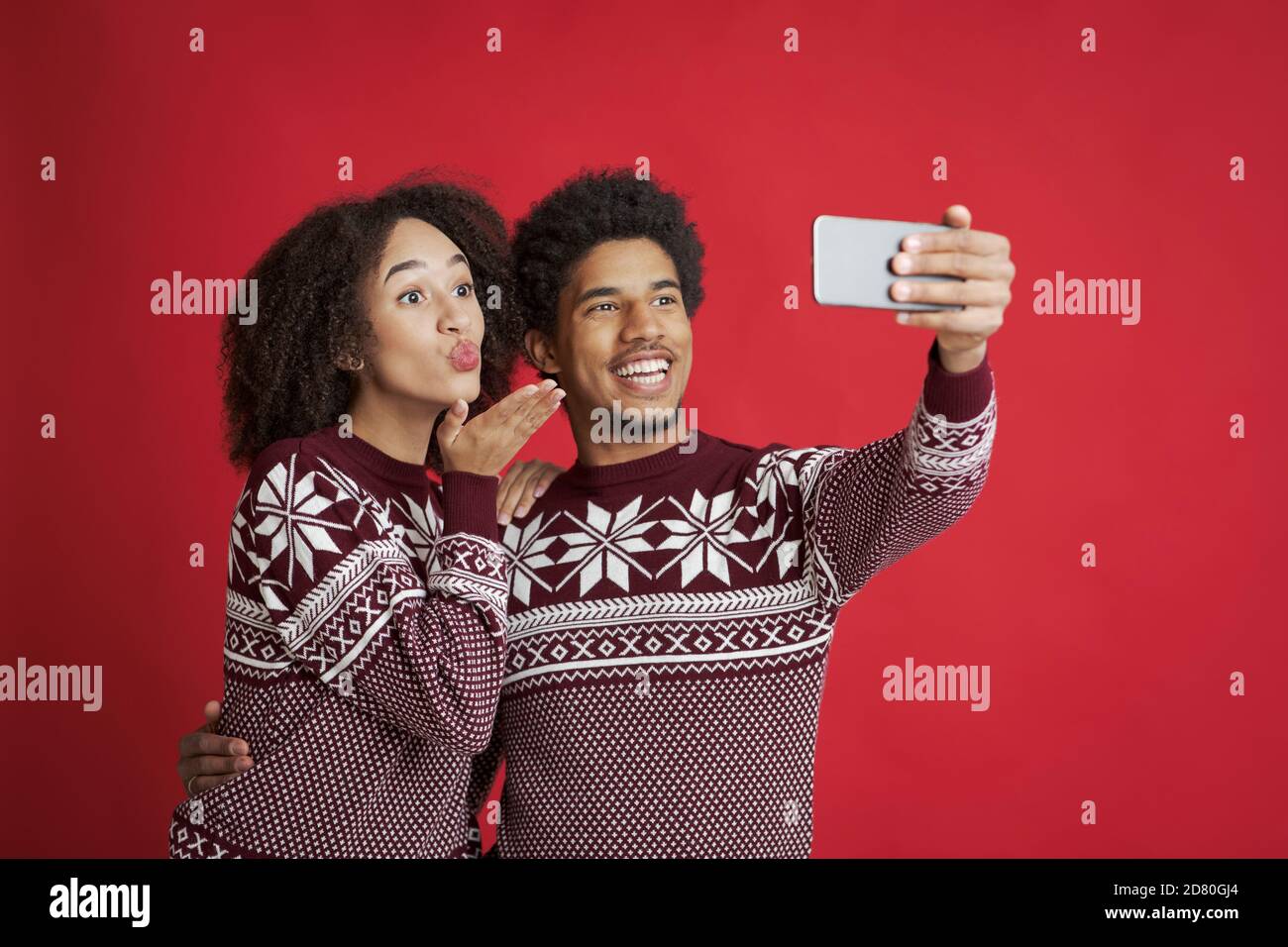 Selfie de couple amoureux. Un homme afro-américain heureux tient un smartphone, une dame qui souffle baiser ou passer un appel vidéo Banque D'Images