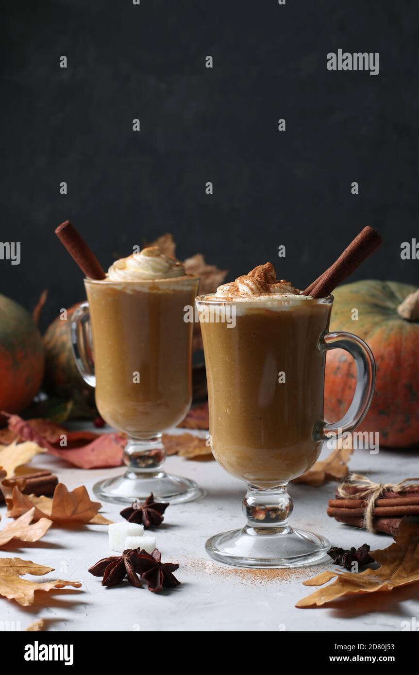 Deux tasses en verre de latte de citrouille aux épices sur fond sombre avec citrouilles et feuilles d'automne, gros plan Banque D'Images