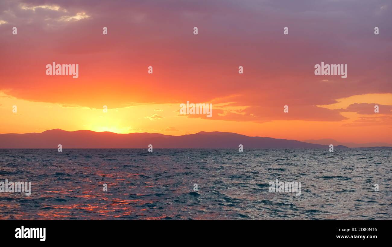 Paysage avec un ciel jaune rouge et des nuages au-dessus de la mer au coucher du soleil. Île d'Aegina, Grèce Banque D'Images