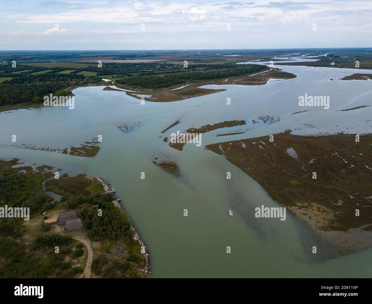 Vue aérienne de la belle lagune de Caorle près de Venise en Italie avec de vieilles maisons de pêcheurs, les gens appréciant l'été à la plage et les bateaux passant par Banque D'Images