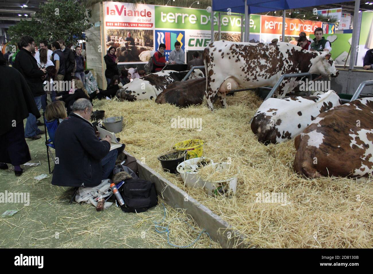 Un couple assis devant un stand de bétail dans le foin. Salon agricole de Paris 2014 Banque D'Images