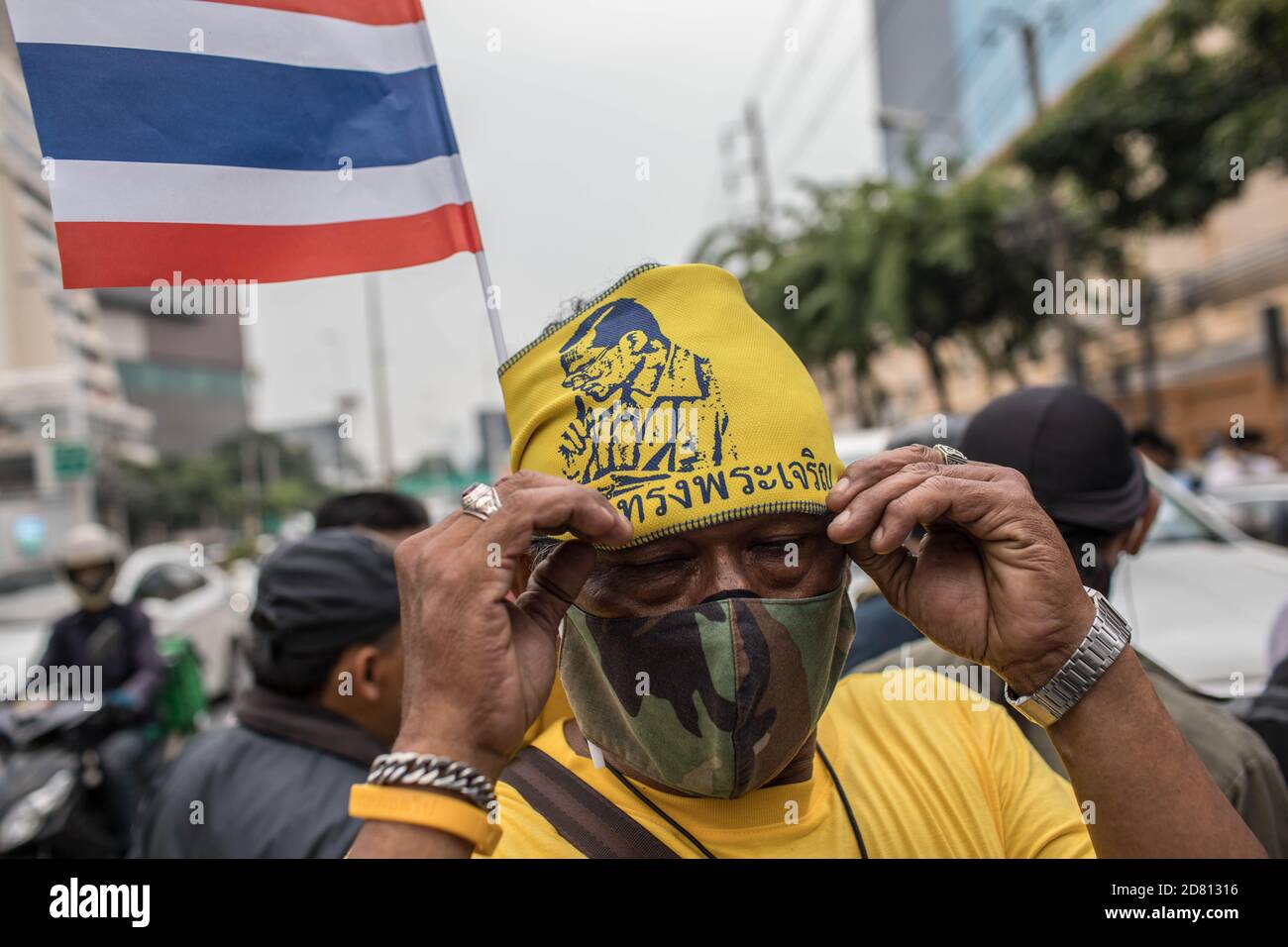 Un protestant pro-monarchie remplace son bandana par le roi Bhumibol Adulyadej (Rama 9) lors d'une manifestation à l'extérieur de l'ambassade d'Allemagne. Les manifestants de chemises jaunes se sont rassemblés devant l’ambassade d’Allemagne à Sathorn Road pour montrer leur soutien à la monarchie. Ils ont également soumis une lettre expliquant la situation politique en Thaïlande à l’ambassadeur Georg Schmidt, qui a été signé par Nitititititorn Lamlua et Pichit Chaimongkol du mouvement du « peuple de Thaïlande ». Banque D'Images