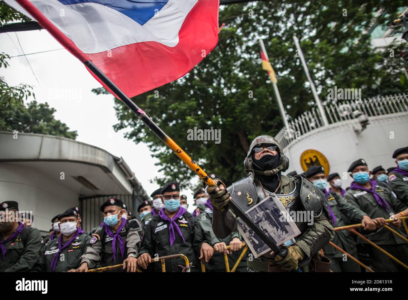 Un protestant pro-monarchie portant une tenue militaire a été vu porter le drapeau de la Thaïlande devant l'ambassade lors d'une manifestation à l'extérieur de l'ambassade d'Allemagne. Les manifestants de chemises jaunes se sont rassemblés devant l’ambassade d’Allemagne à Sathorn Road pour montrer leur soutien à la monarchie. Ils ont également soumis une lettre expliquant la situation politique en Thaïlande à l’ambassadeur Georg Schmidt, qui a été signé par Nitititititorn Lamlua et Pichit Chaimongkol du mouvement du « peuple de Thaïlande ». Banque D'Images