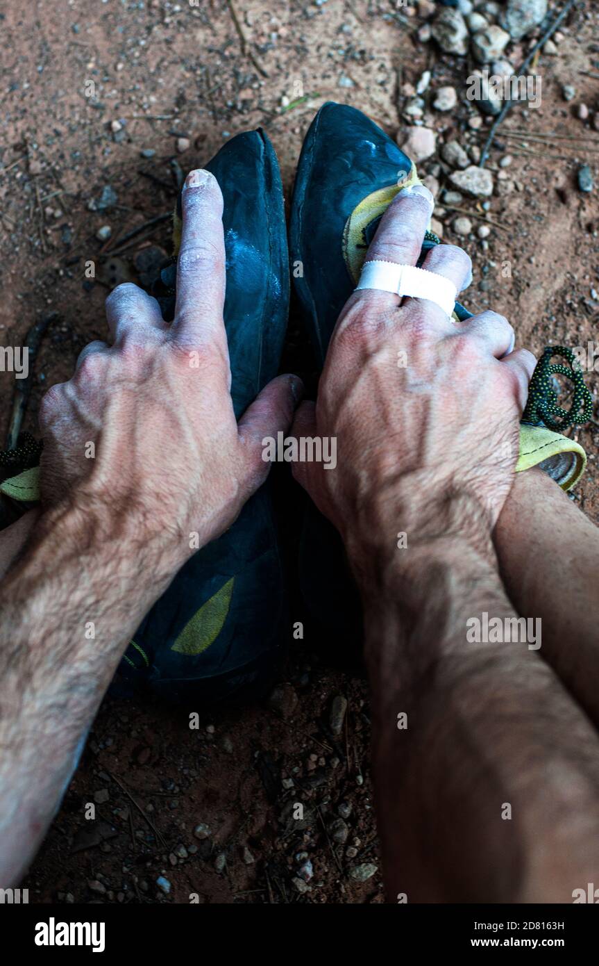 Les mains d'un grimpeur saisissant ses pieds, se reposant après l'effort. Banque D'Images