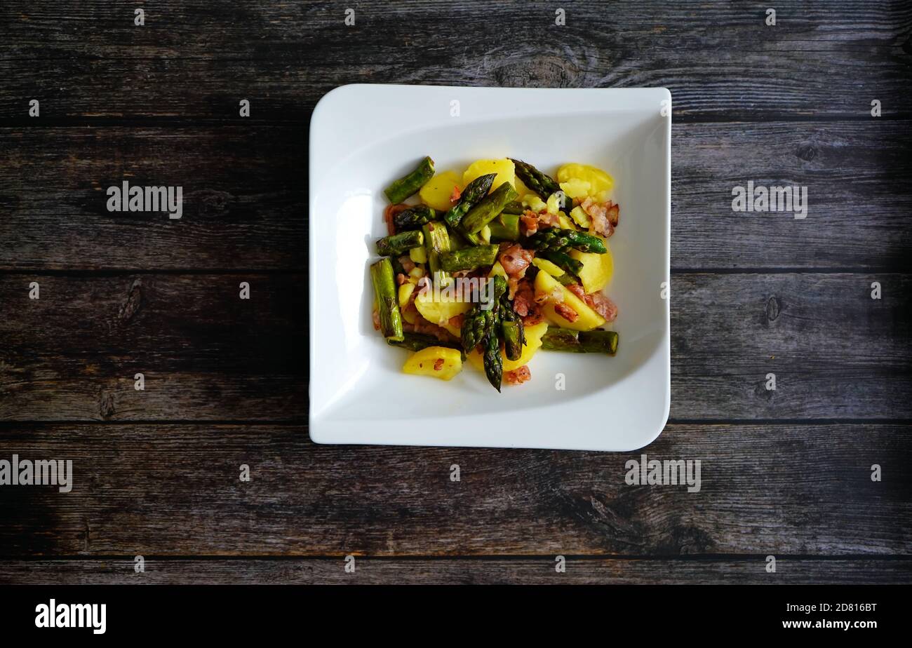 Asperges vertes frites et salade de pommes de terre chaude avec bacon et oignons. Cuisine traditionnelle allemande maison. La salade de pommes de terre est un plat allemand populaire. Banque D'Images