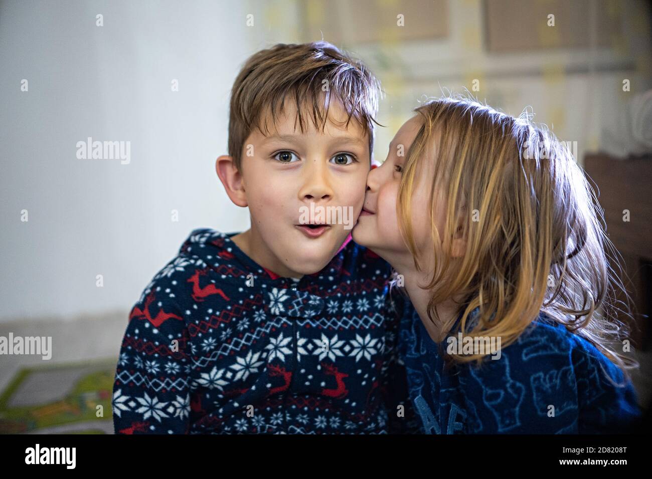 Deux frères et sœurs en pyjama avec livre, soeur baiser frère, drôle émotions énorme maison Banque D'Images