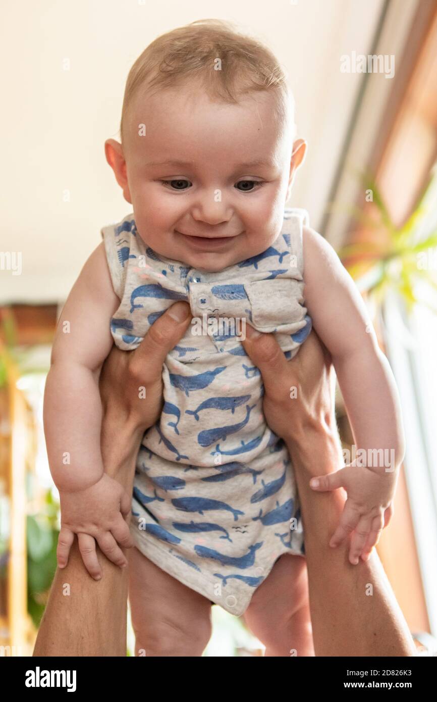 Concentration Selective Des Mains Du Jeune Pere Tenant Le Bebe Souriant Enfant Dans L Air Et Jouant En Etant Allonge Sur Le Canape A Accueil Photo Stock Alamy
