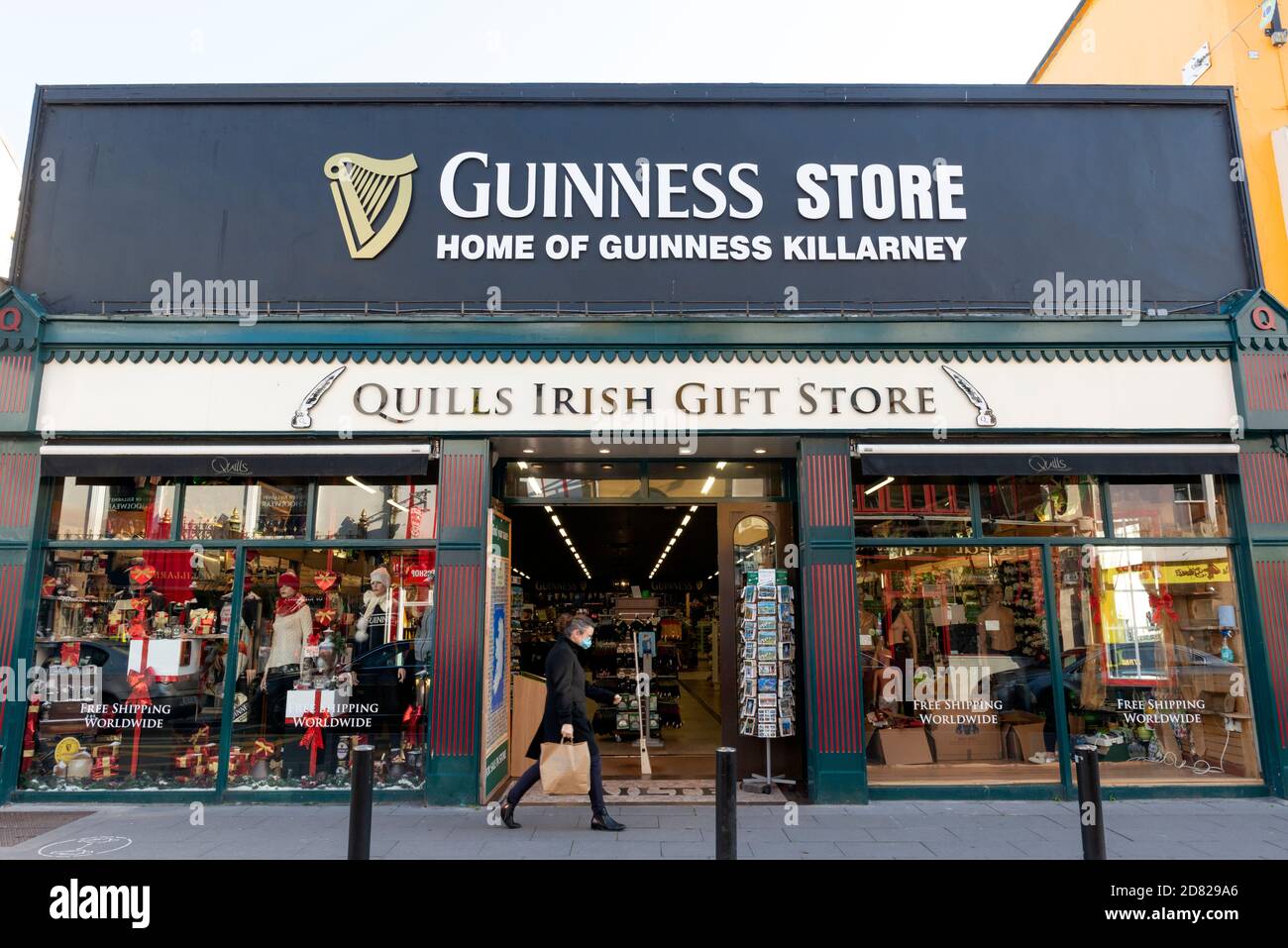 Homme portant un masque de visage passant par le Guinness Store et Quills Irish Gift Store dans High Street Killarney County Kerry Irlande Banque D'Images