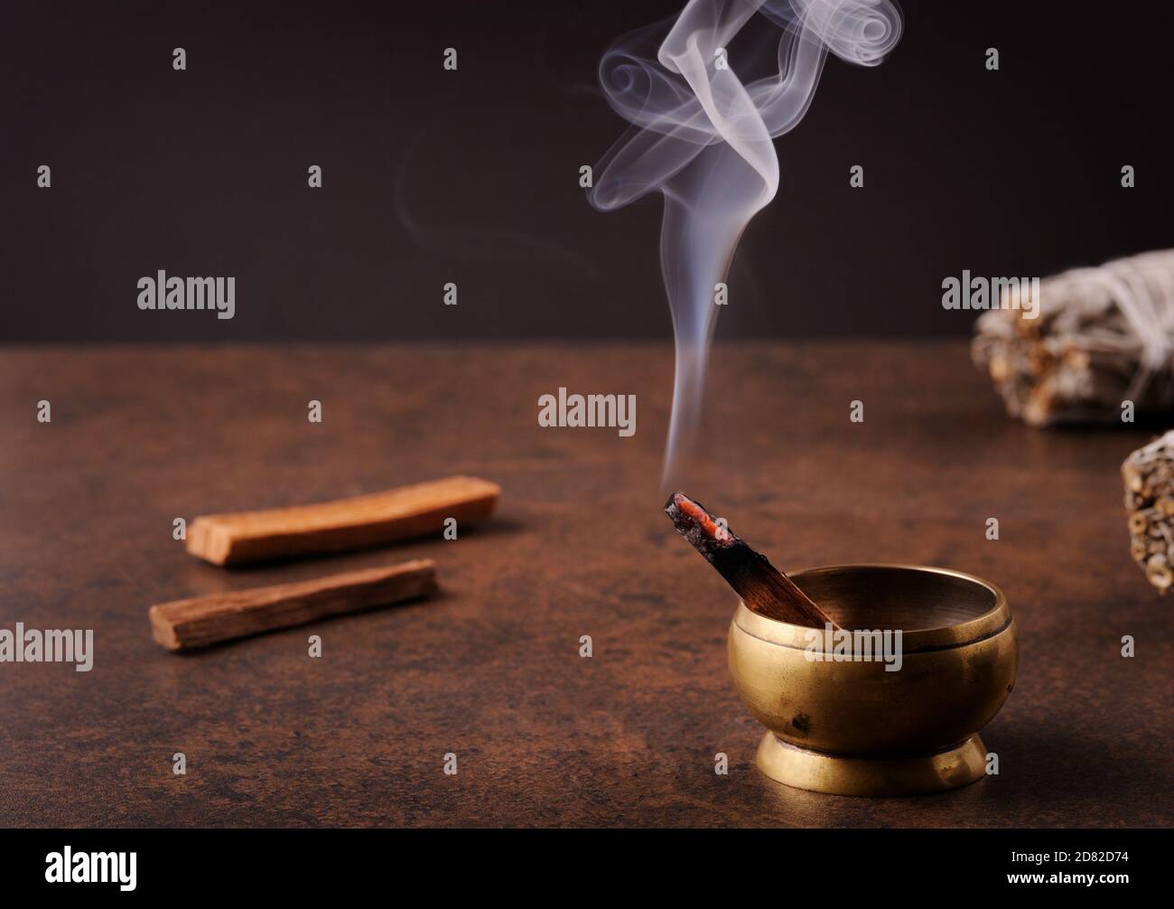 Bâton aromatique Pala Santo brûlant et fumant sur fond brun foncé. Le concept de purification du corps et de l'âme, de guérison, de méditation. Banque D'Images