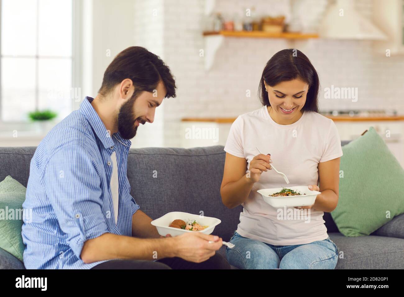 Jeune couple assis sur un canapé à la maison et déjeuner commandé dans le service de livraison de nourriture Banque D'Images