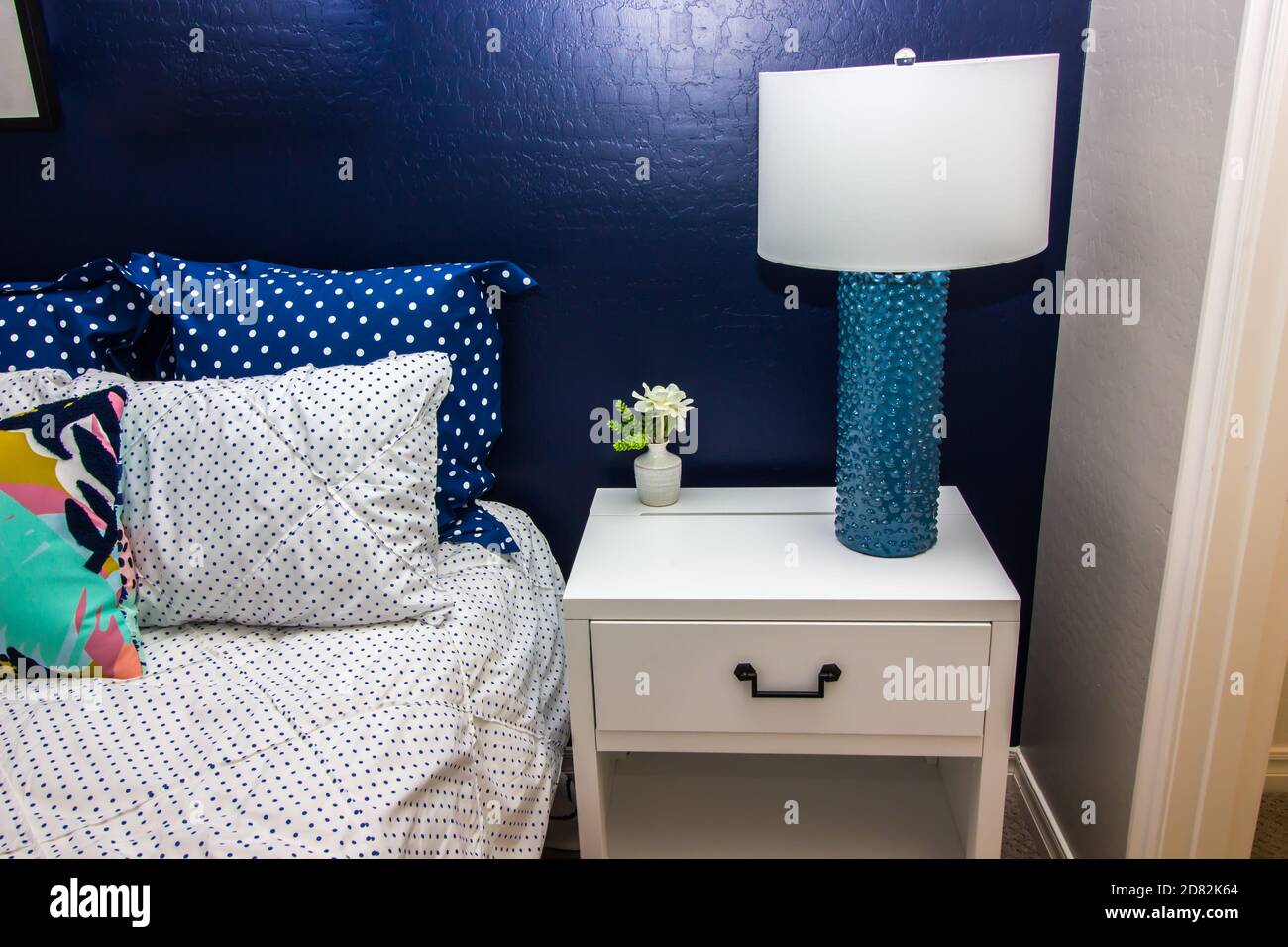 Chambre avec mur d'appoint bleu, lit, table de nuit et lampe décorative Banque D'Images