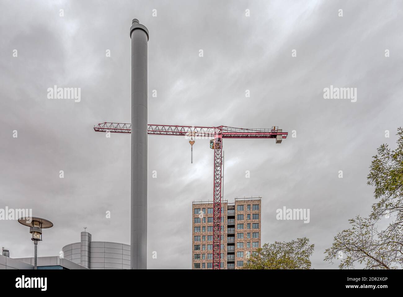 Immeuble derrière une cheminée de chauffage avec une grue de construction rouge, Frederikssssund, Danemark, 25 octobre 2020 Banque D'Images